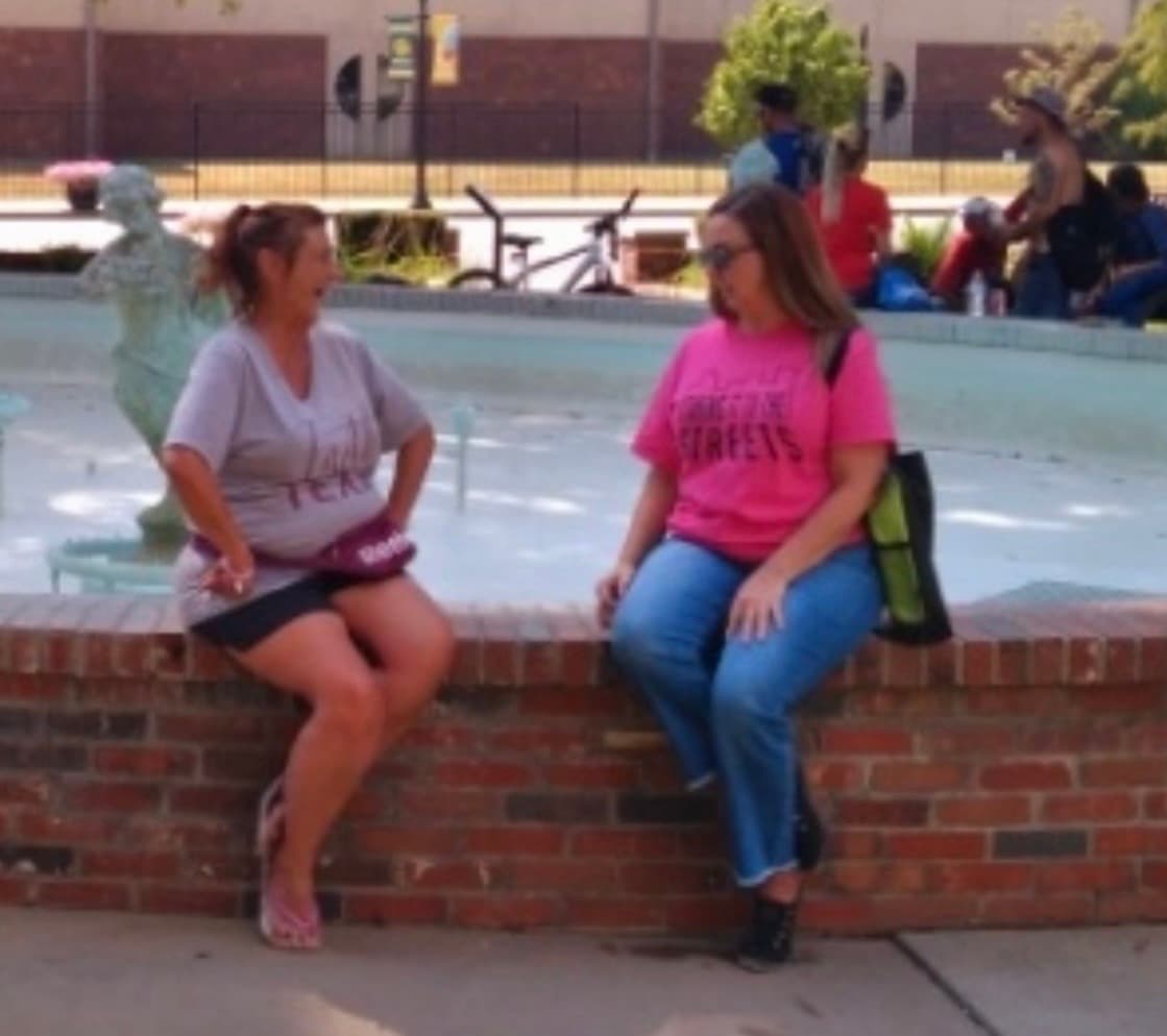 Two outreach team members talking beside a public fountain during a community outreach visit.