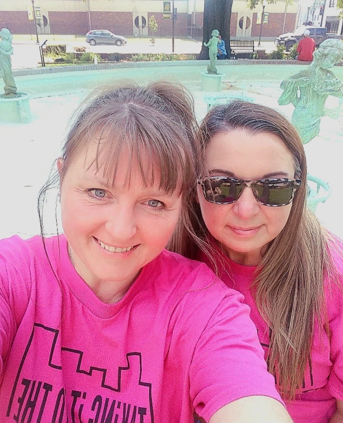 Two Street Outreach team members wearing pink team shirts at a public fountain.